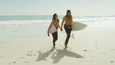 Pareja-Con-Tabla-De-Surf-Caminando-Por-La-Playa-4k-4k