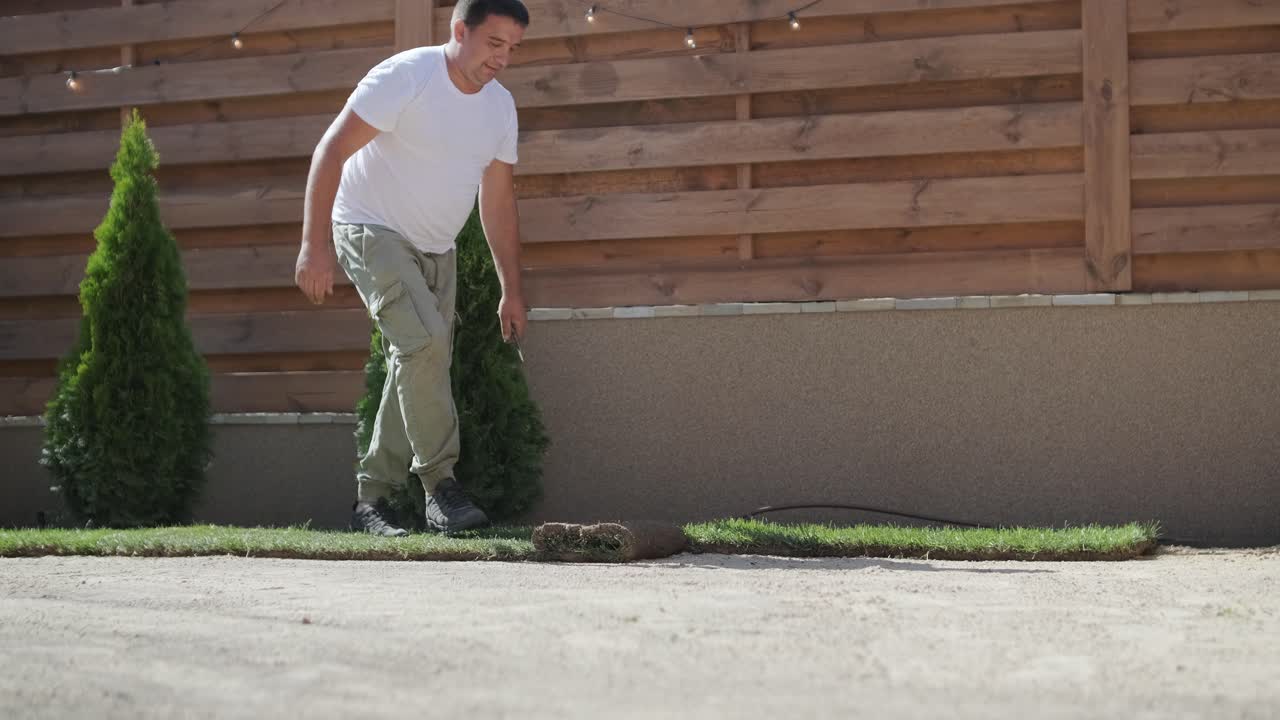 hombre colocando césped en el jardín del patio trasero para la instalación de césped y proyecto de jardinería, centrado en la mejora del hogar y el mantenimiento al aire libre para un césped fresco y verde en un patio residencial