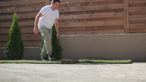 man laying sod grass in backyard garden for lawn installation and landscaping project, focused on home improvement and outdoor maintenance for a fresh, green lawn in a residential yard