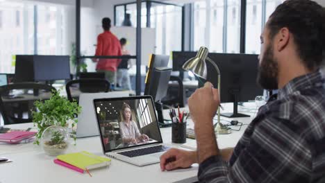 Mixed-race-businessman-sitting-at-desk-using-laptop-having-video-call-with-female-colleague