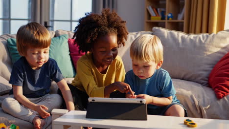 three children watching a tablet together on a couch