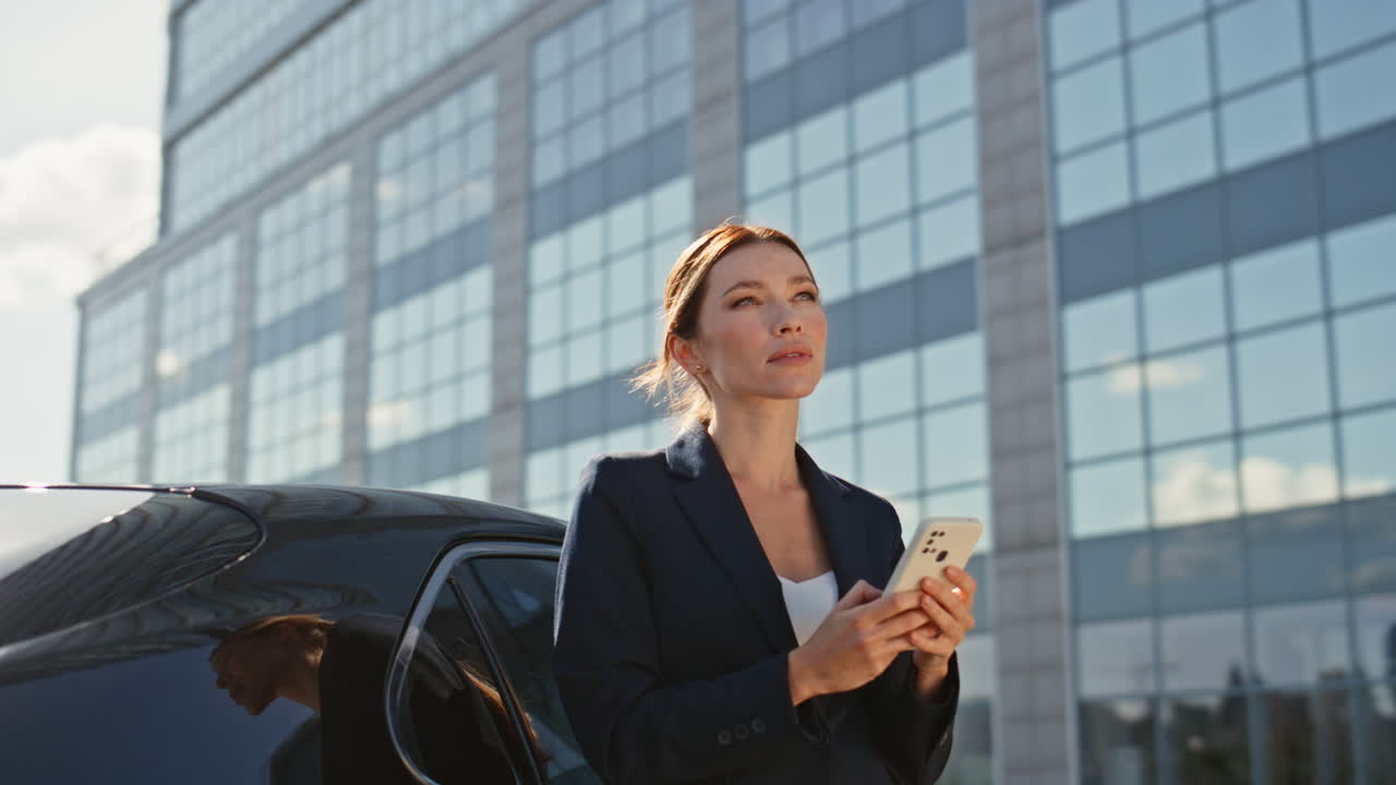 현대적인 사무실 건물 밖에서 스마트폰을 스크롤하는 기업 매니저.