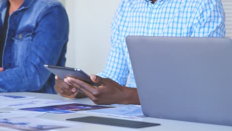 Mid-section-of-business-team-working-on-laptop-and-digital-tablet-in-modern-office-4k