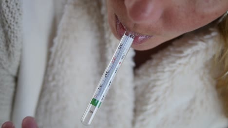 close-up of a sick woman taking her oral temperature