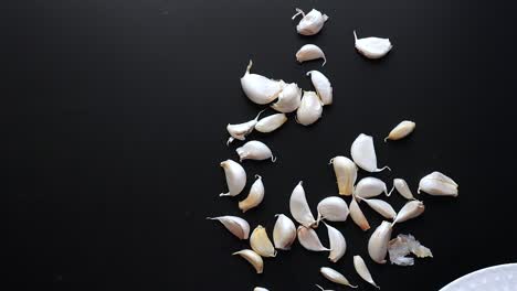 scattered garlic cloves on black background