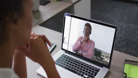 Mittelteil-Einer-Afroamerikanischen-Frau,-Die-Im-Büro-Einen-Videoanruf-Mit-Einem-Männlichen-Kollegen-Auf-Einem-Laptop-Führt