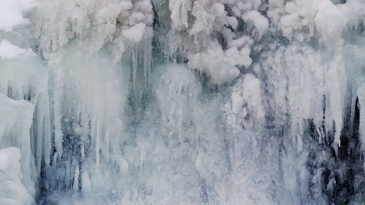 Ruscello che scende a cascata dietro la cascata ghiacciata di Resovsky con stalattiti di ghiaccio invernali. Scena naturale fredda ideale per paesaggi, immagini stagionali e uso documentaristico