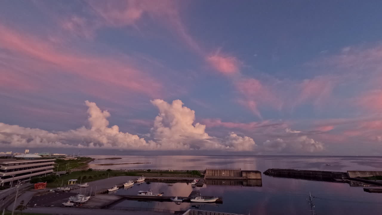 Static time-lapse shot of Cumulonimbus Clouds billowing towards the stratosphere, over the ocean while being illuminated from a deep pink through orange to yellow as the sunrises