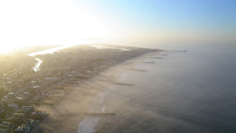 aerial view of a coastal city with beach and river at sunrise or sunset