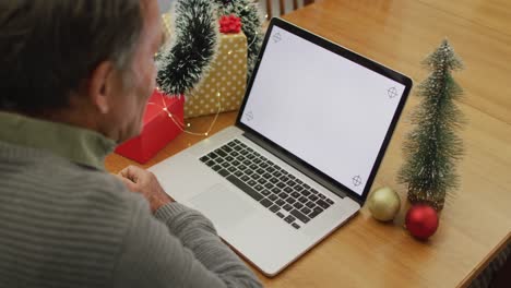 Caucasian-senior-man-sitting-at-table-making-video-call-at-home-on-laptop-with-copy-space-on-screen