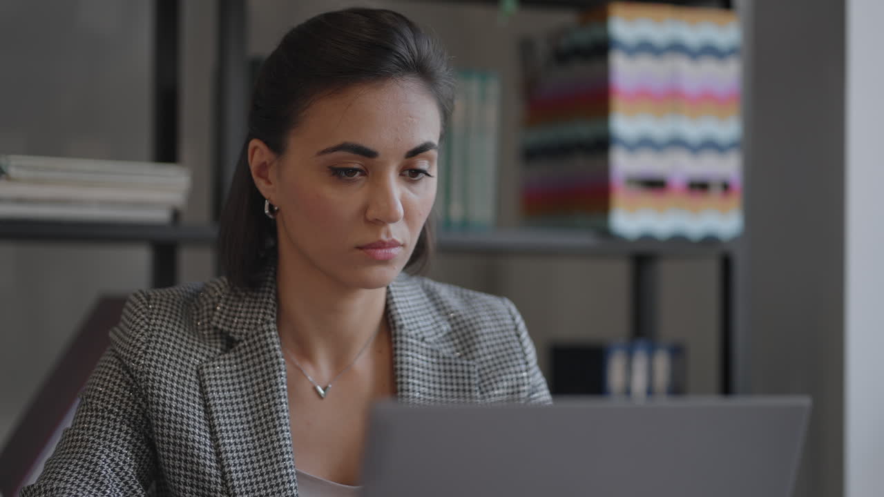una joven hermosa está sentada en una silla y escribiendo o tomando notas mientras asiste a una clase de video en línea o a una reunión de oficina en una computadora portátil. mujer musulmana moderna que trabaja en línea de forma remota