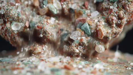 an intricate close-up of multi-colored particles flowing and intermingling, showcasing the unique texture and movement of compacted material over time