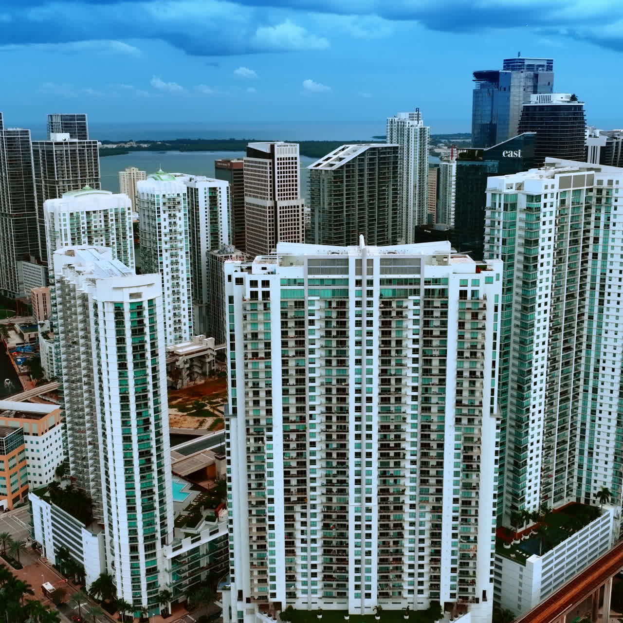 Multiple apartment blocks built in Miami Beach district. Cloudy sky above the Atlantic Ocean at backdrop. Top view.