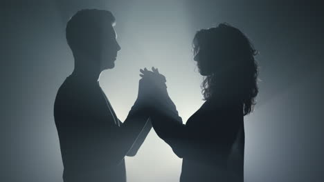 sensual couple silhouette holding hands indoors. lovers standing in dark space