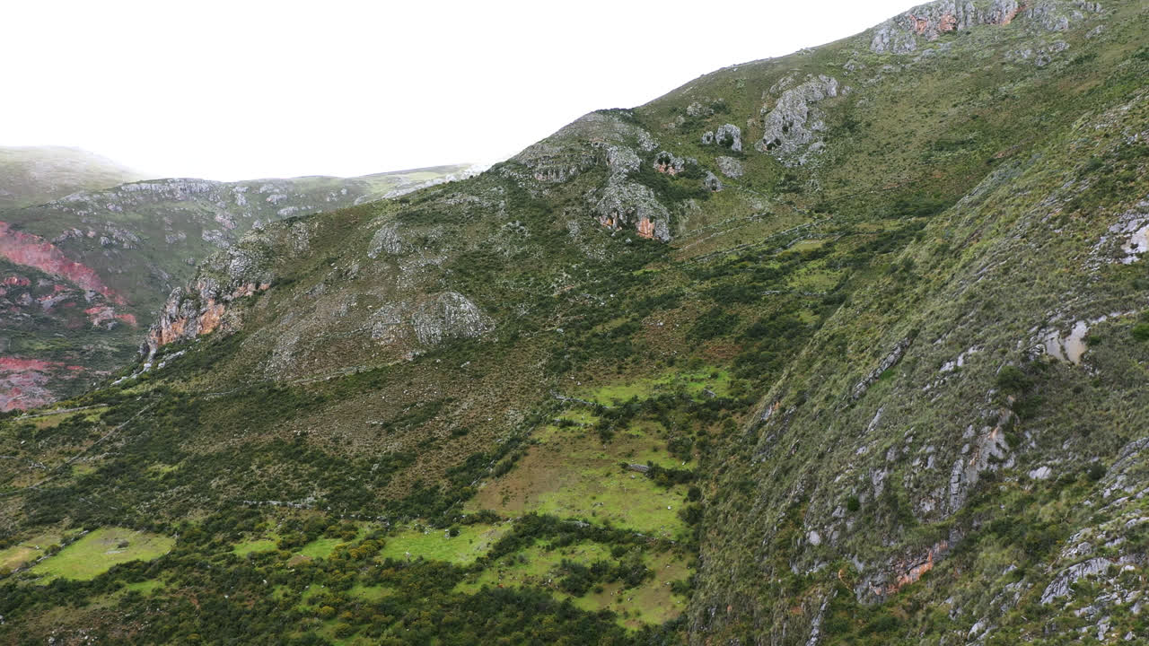 Splendida ripresa aerea con drone di una vetta montuosa ricoperta di vegetazione durante un pomeriggio estivo
