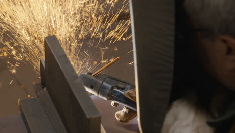 man welding metal frame with a lot of sparkles flying by slow motion detail shot