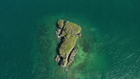 overhead aerial view of a small island in clear tropical aqua pacific water in 4k