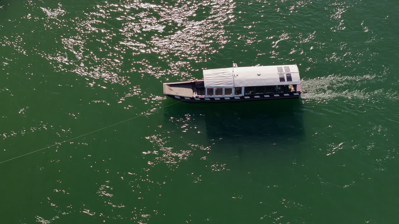 Top-down view of Basel Rhine ferry gliding on calm green waters under bright sunlight