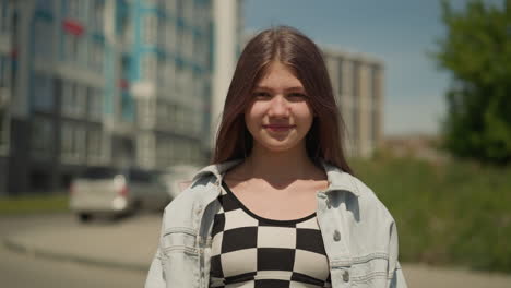 uma adolescente de cabelo liso está na rua de uma grande cidade