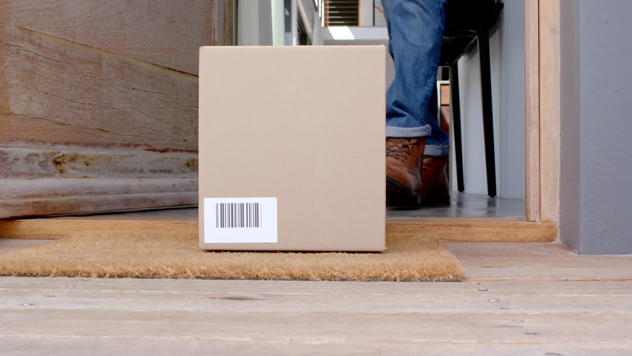 Receiving package, person standing at doorstep holding cardboard box
