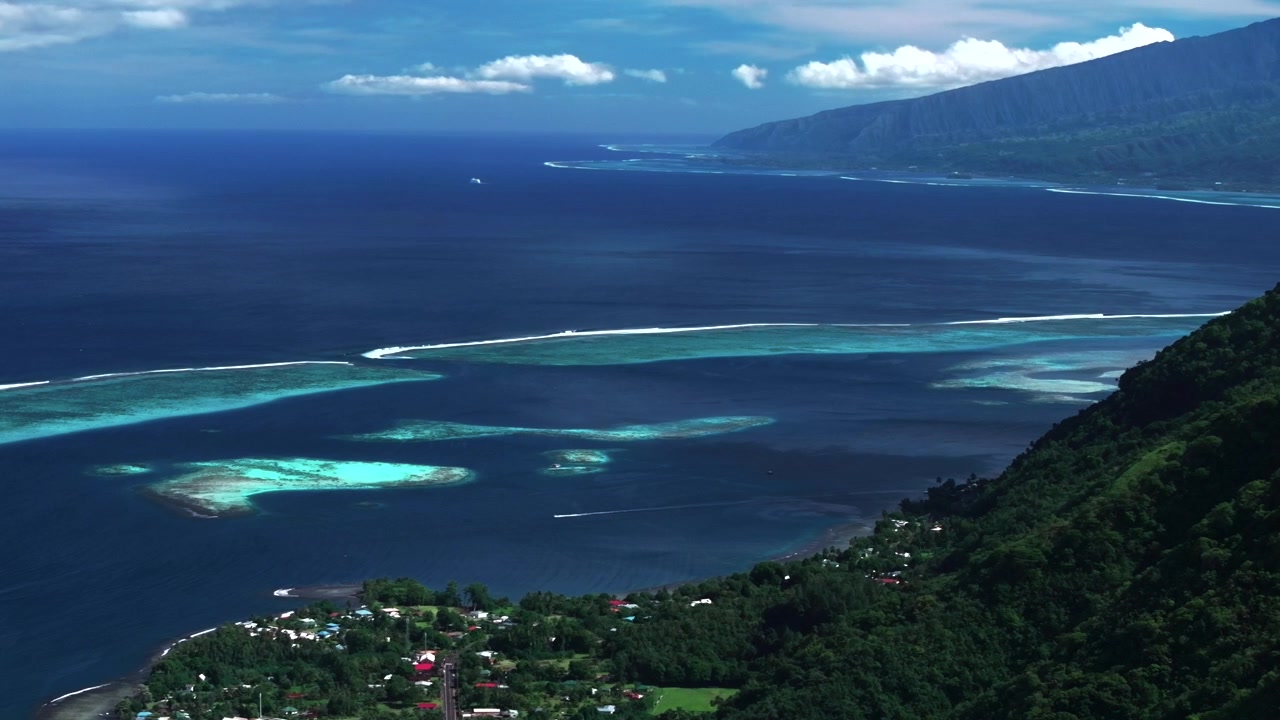 Koralrevsbrænding af Teahupoo-bølgen Tahiti Fransk Polynesien luftbåren drone parallakse kyst morgen solrig blå himmel kanalbugt Papeete Paris OL 2024 surf surfer surfersted cirkel venstre parallaksebevægelse