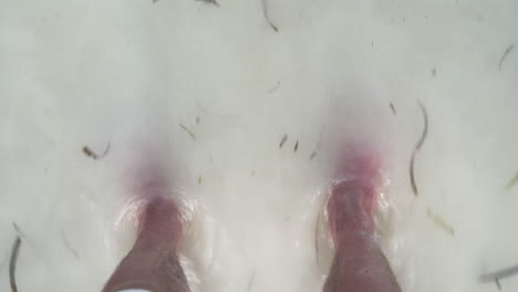 feet standing on white sand beach, washed by sea waves, close up