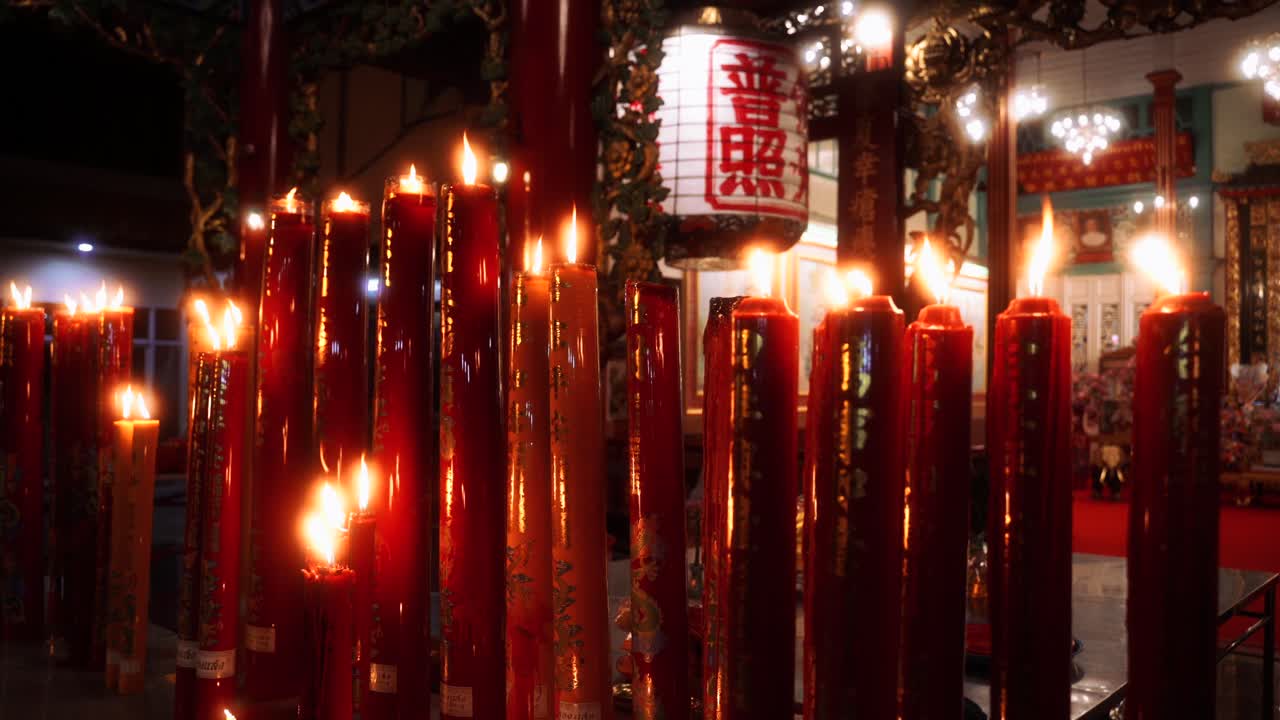 Candles glow inside Chinese Buddhist temple, warm ambient flame lighting and quiet reverence