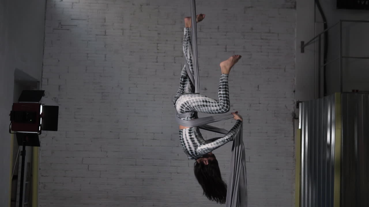 mujer artista de circo practicando un ejercicio acrobático de seda aérea en su estudio