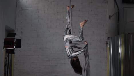 mujer artista de circo practicando un ejercicio acrobático de seda aérea en su estudio