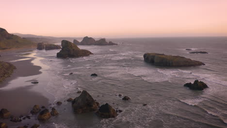 aerial of sea stacks at the southern oregon coast during a moody pink sunset