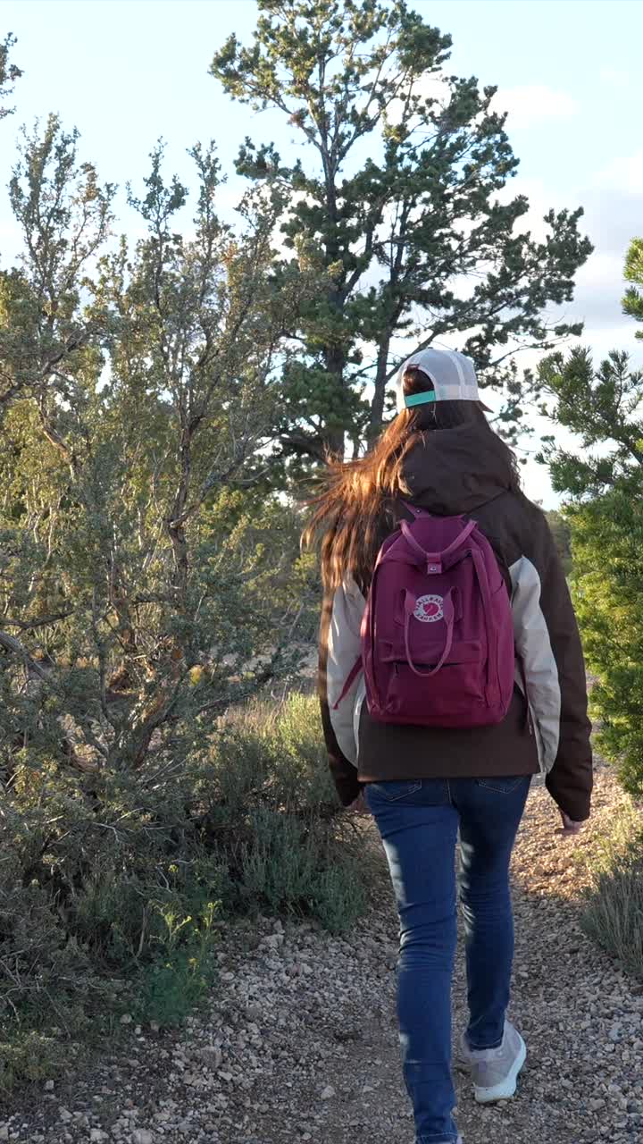 Donna con zaino che cammina su un sentiero naturalistico panoramico.