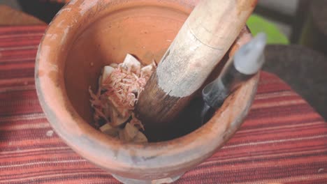 cooking som tam series: slo mo street food vendor's hand putting dried shrimp in mortar to make som tam or thai spicy green papaya salad, one of thailand's most popular dishes