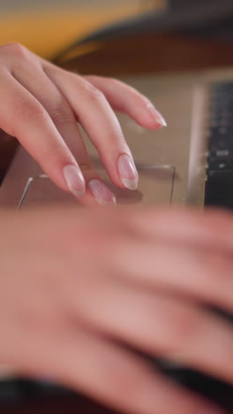 manos femeninas en vestido rosa sentadas en el centro comercial, trabajando con una computadora portátil, usando el touchpad y escribiendo, la escena se centra en la tarea a la mano con una elegante postura de escritura en un espacio público