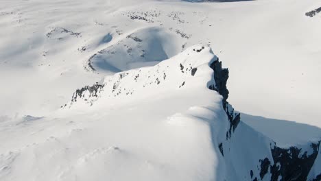 Flying-down-majestic-mountain-ridge-covered-in-snow-in-FPV-drone