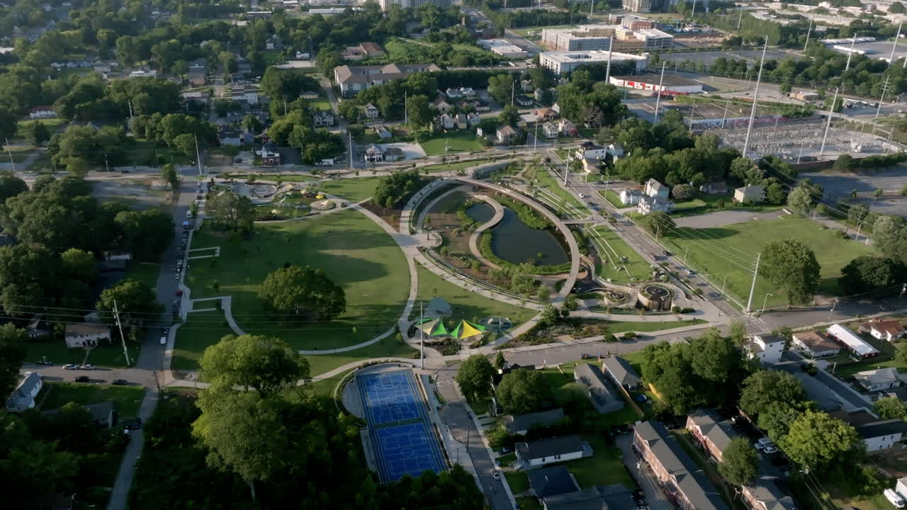 Aerial shot of a park in Atlanta with winding paths, pond, and city skyline in the distance
