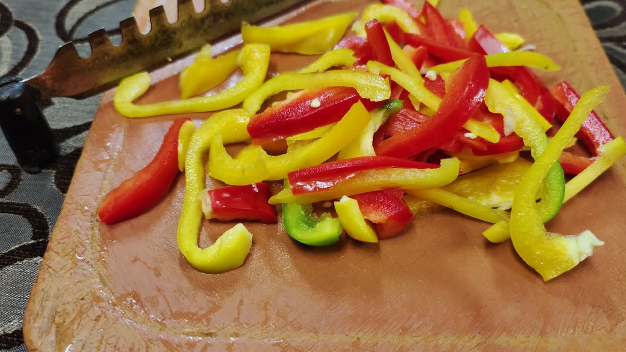 신선한 빨간색과 노란색 고추는 스테인리스 스 칼날로 갈색 채소 절단기에 어