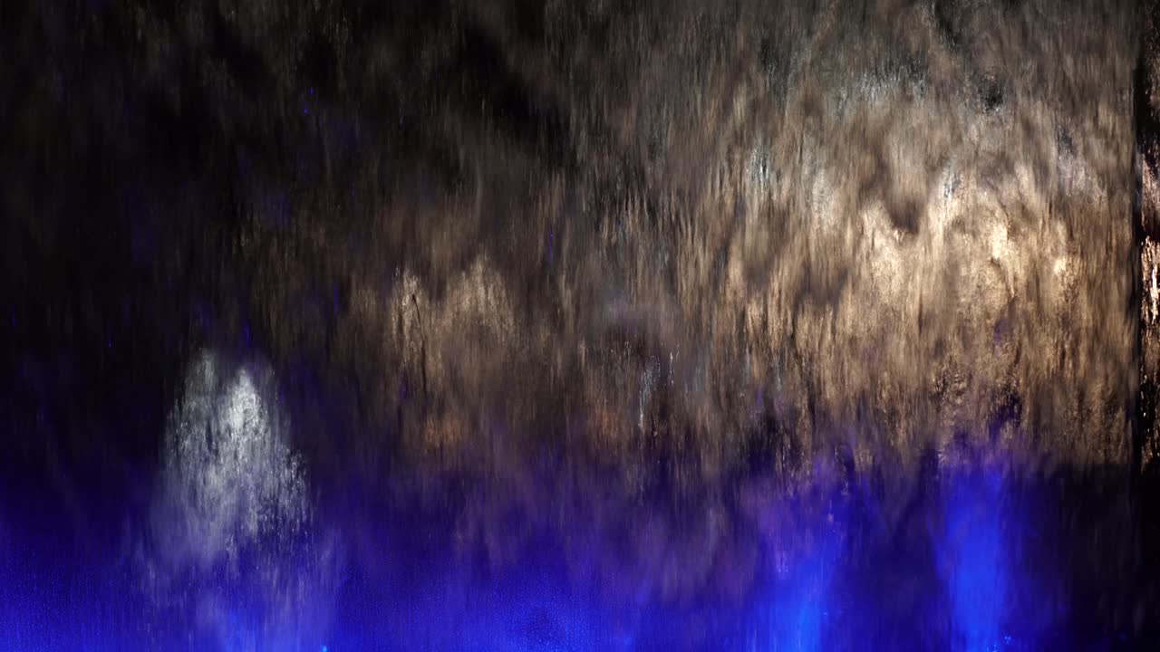 fuente moderna en la plaza de la ciudad con luces de colores bajo el agua que reflejan las luces de los coches y las siluetas en el fondo nocturno