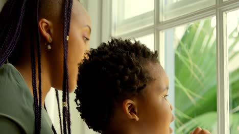 primer plano de una joven madre negra jugando con su hijo en el alféizar de la ventana en una casa cómoda 4k