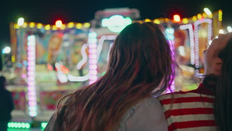 closeup happy girls sharing secrets at funfair. two friends gossiping laughing