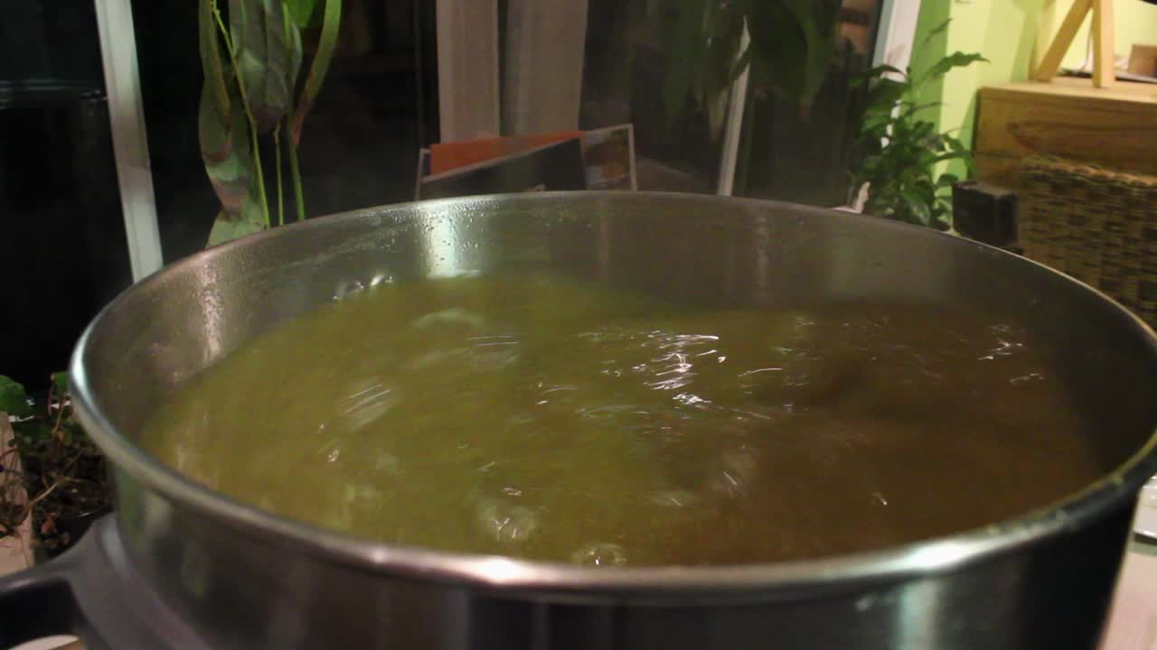 Timelapse del mosto caldo e marrone di una birra nella sua fase iniziale, mescolato rapidamente in un secchio da birraio in acciaio inossidabile.