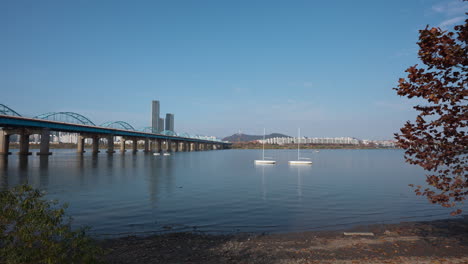 han river bank with small sailboats moored on hangang near dongjak bridge on autumn sunny day - establishing static view