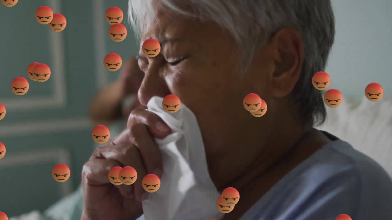 Animation of emoji icons over senior biracial woman with runny nose in bed