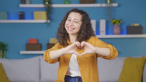 mujer joven haciendo una señal de corazón a la cámara.