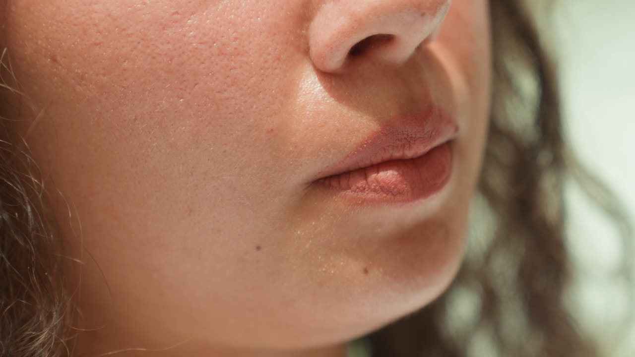 Calm glowing face. Relaxed mouth illuminated softly by tranquil soothing luminous surroundings. Closeup image of serene lips softly glowing under gentle peaceful and calming light effects