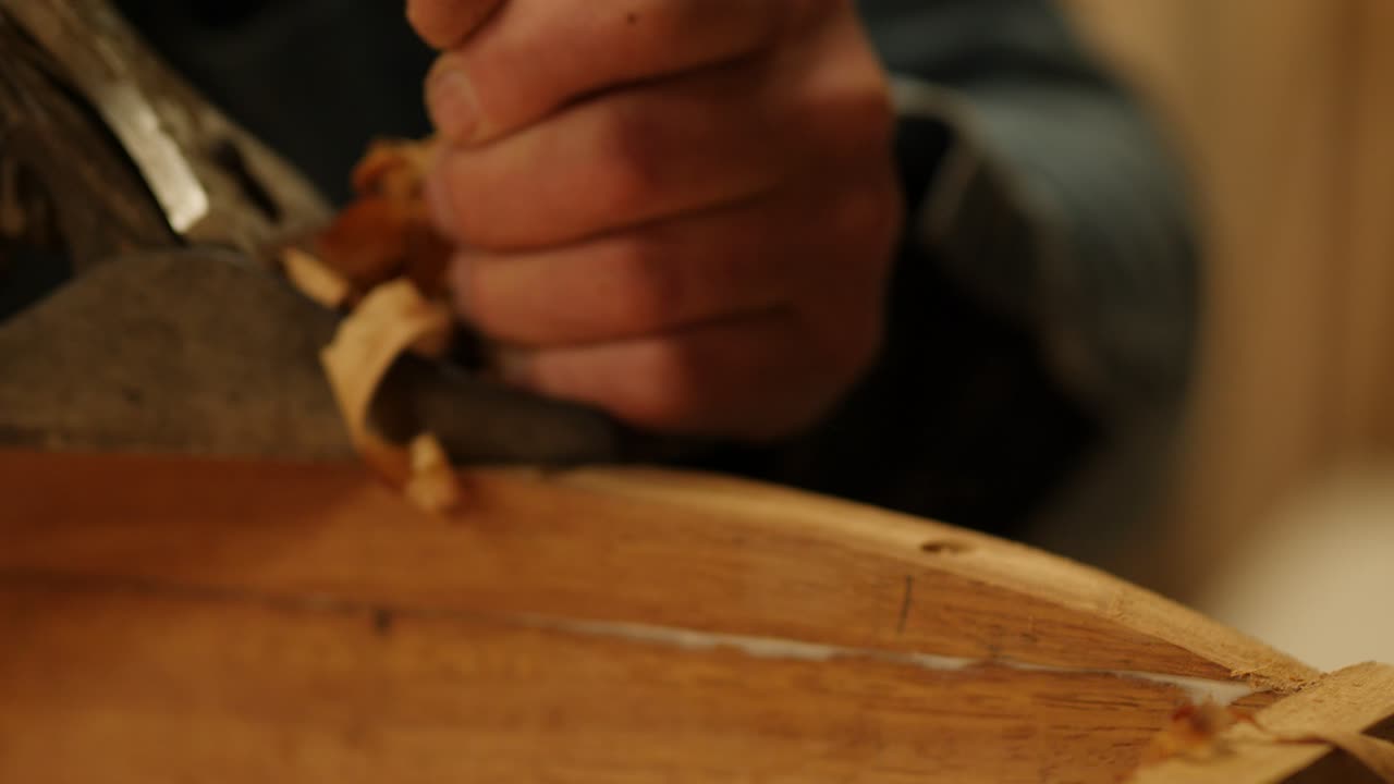 Close-up of a craftsman using a hand plane to smooth a wooden surface