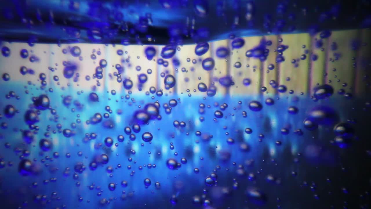 vista ampliada de las burbujas de aire dentro de una botella grande de desinfectante de manos ya que el fondo es colorido y cambiante