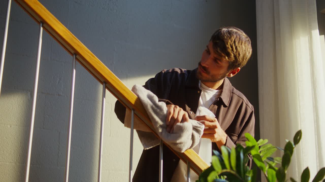 hombre limpiando la barandilla de la escalera de madera y metal