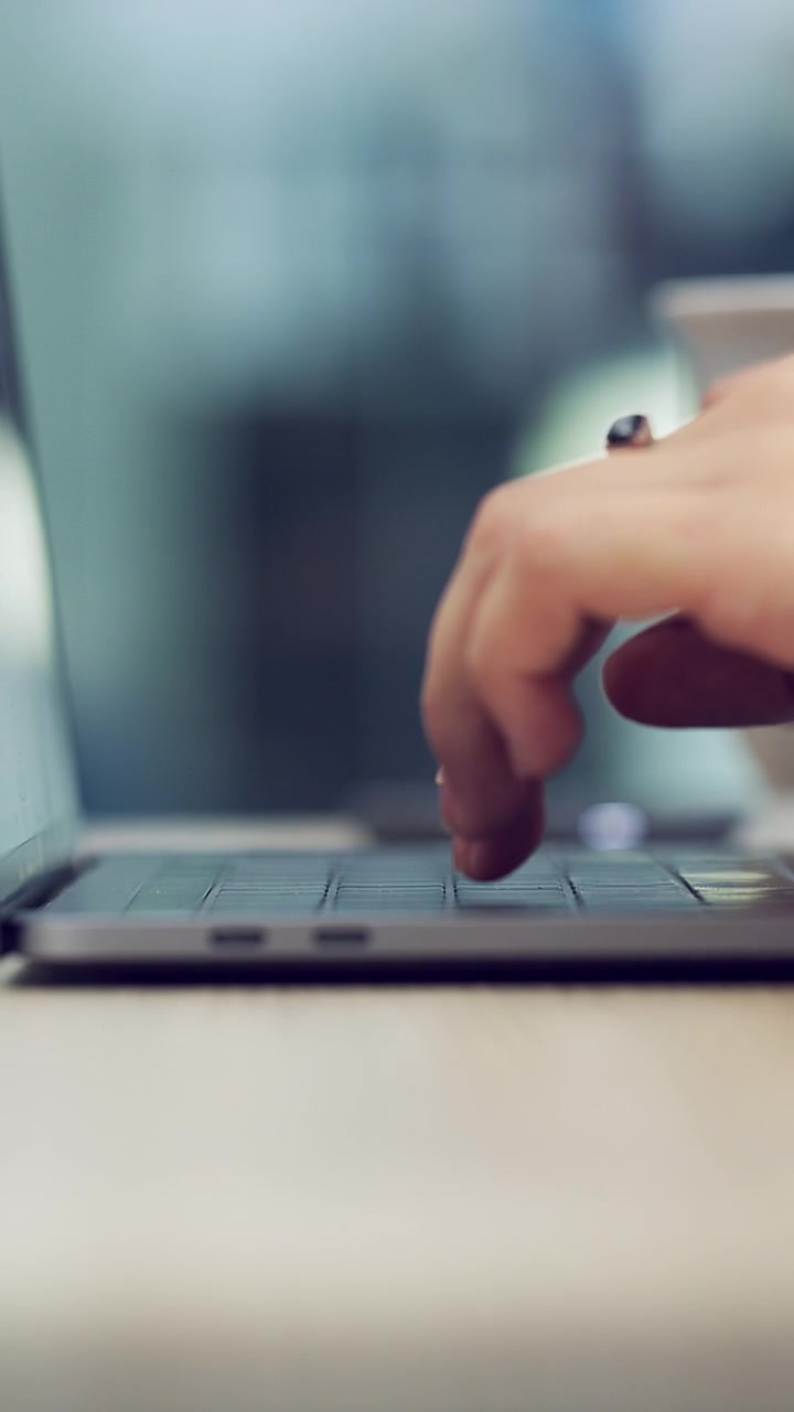 Primo piano di una persona che digita sulla tastiera del laptop in ufficio
