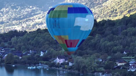 hot air balloon taking off by the lake and rising up above the mountains