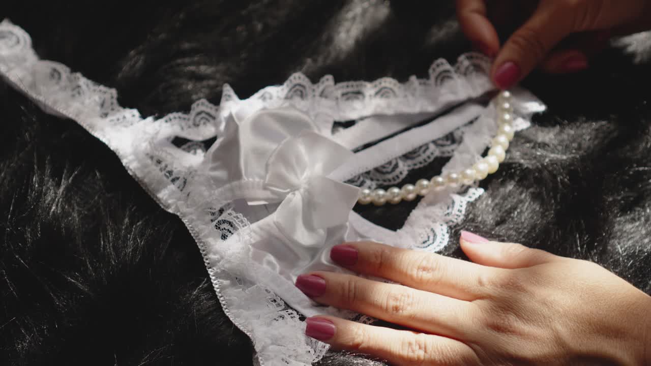 White lace lingerie with pearls placed by a woman's hand